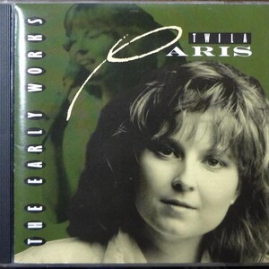 May include: CD case for "The Early Works" by Twila Paris. The cover features a sepia-toned portrait of a woman with short hair, overlaid with a white script "Paris" and a green background with a faded image of the same woman.