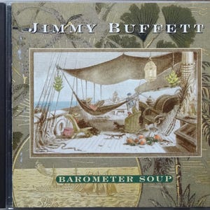 May include: CD case for Jimmy Buffett's album, "Barometer Soup." The cover features an illustration of a ship's deck with a hammock, figures, and fruit. The album title is in a green and gold design.