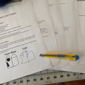 May include: Instructions for making a foam head base and liner for a costume. The instructions include a materials list, assembly instructions, and diagrams of the foam base and liner patterns. The image also shows a ruler and a utility knife.