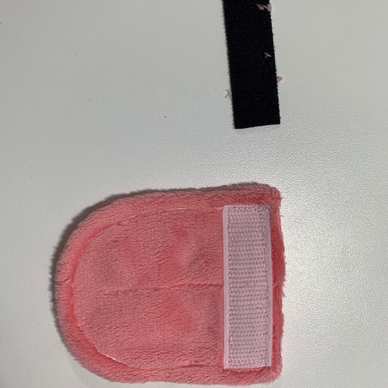 Op de afbeelding: Een roze pluche stoffen hoofdband met een roze klittenbandsluiting.
