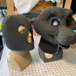 May include: Two foam head bases for fursuit making. The one on the left is a human head base with eye holes. The one on the right is a furry head base with a snout and eye holes.