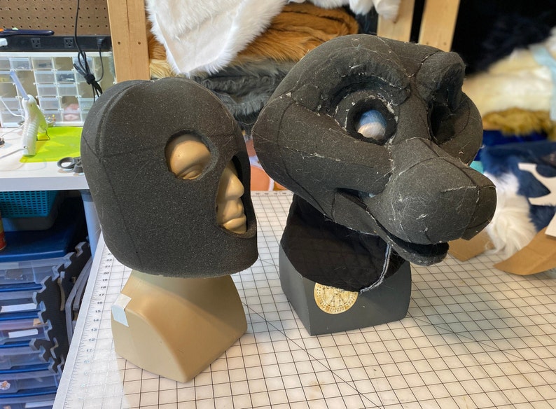 May include: Two foam head bases for fursuit making. The one on the left is a human head base with eye holes. The one on the right is a furry head base with a snout and eye holes.