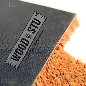 a logo for a company called "Wood by Stu" with a textured background and a wooden plank design.