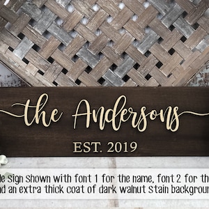 May include: A wooden sign with the text "the Andersons EST. 2019" in a gold font. The sign has a dark walnut stain background.
