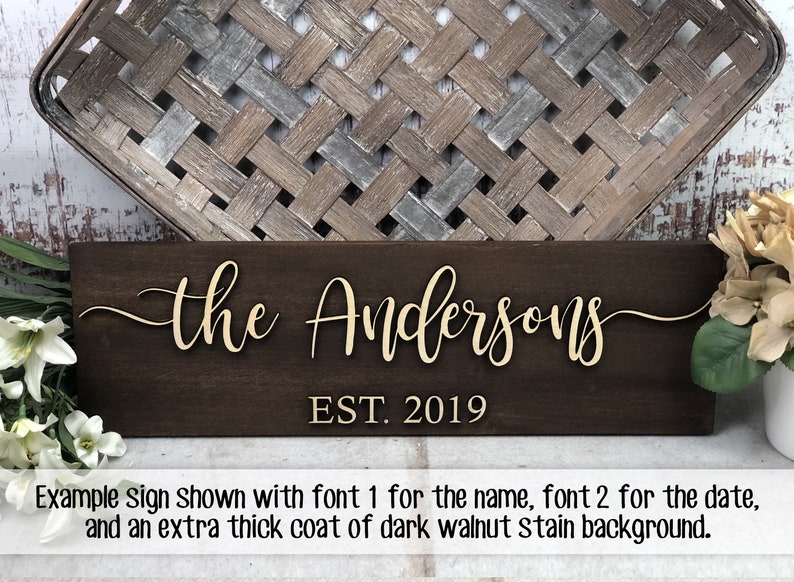 May include: A wooden sign with the text "the Andersons EST. 2019" in a gold font. The sign has a dark walnut stain background.
