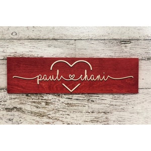May include: A red wooden sign with the names "paul & chani" written in cursive with a heart symbol between the names.