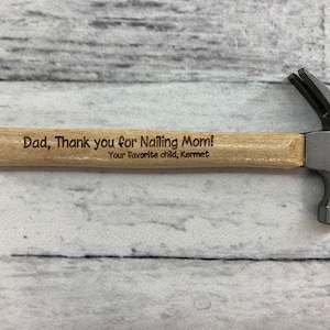 May include: A small wooden handled hammer with a metal head. The handle is engraved with the text "Dad, Thank you for nailing Mom! Your favorite child, Kermet".