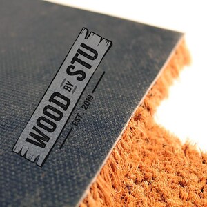 a close-up of a textured surface, possibly a carpet or mat, with a logo or text overlay in the center.