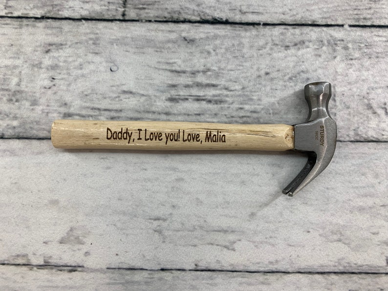 May include: A small wooden handled hammer with a metal head. The handle is engraved with the message "Daddy, I love you! Love, Malia".