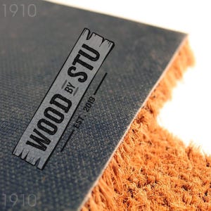 a close-up of a textured surface, possibly a carpet or mat, with a logo or text overlay in the center.