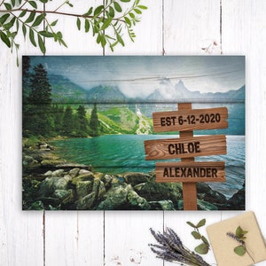 May include: A wooden sign with a mountain lake background. The sign has three lines of text: "EST 6-12-2020", "CHLOE", and "ALEXANDER".