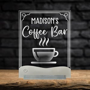 May include: A white illuminated sign with the text "MADISON'S Coffee Bar" and a stylized image of a coffee cup with steam rising from it.