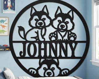 May include: A circular black wall sign featuring a cutout design of three husky-style dogs and the name JOHNNY in capital letters. Two dogs are positioned above the name, while the third dog is visible at the bottom of the circular frame.