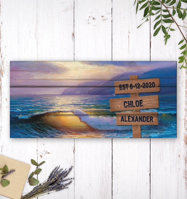May include: A wooden sign with a beach scene background. The sign has three lines of text: "EST 6-12-2020", "CHLOE", and "ALEXANDER".