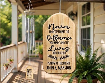 May include: A wooden hanging sign with rounded top edges featuring black text that reads Never Underestimate The Difference You Made And The Lives You Touched Happy Retirement! John R. Marston, paired with a silver metal wind chime hanging nearby.