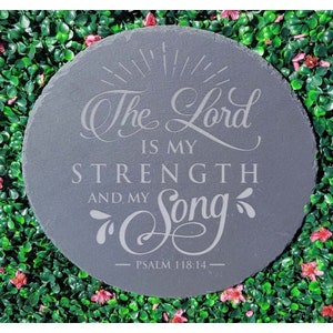 May include: A round gray slate coaster with the text "The Lord is my strength and my song - Psalm 118:14" engraved in white.