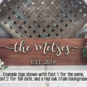 May include: A wooden sign with the text "the Metzes EST. 2019" in a cursive font. The sign is stained a reddish brown color.