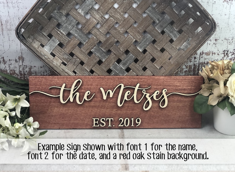 May include: A wooden sign with the text "the Metzes EST. 2019" in a cursive font. The sign is stained a reddish brown color.