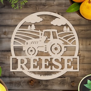 May include: A wooden cutout of a tractor in a field with a name, "REESE", below it. The cutout is in the shape of a circle and has a rustic wood grain.