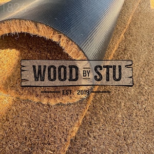 a close-up of a textured surface, possibly a carpet or mat, with a logo or text overlay in the center.