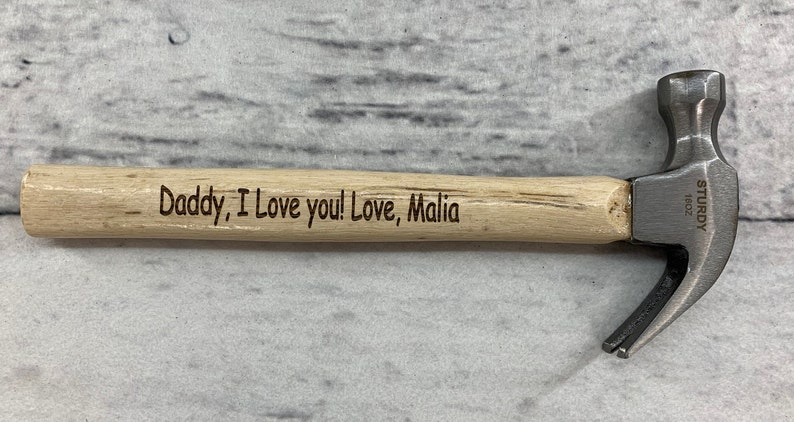 May include: A small wooden handled hammer with a metal head. The handle is engraved with the message "Daddy, I love you! Love, Malia".