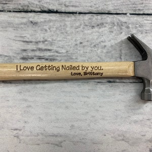 May include: A small wooden handled hammer with a metal head. The handle is engraved with the text "I Love Getting Nailed by you. Love, Brittany."