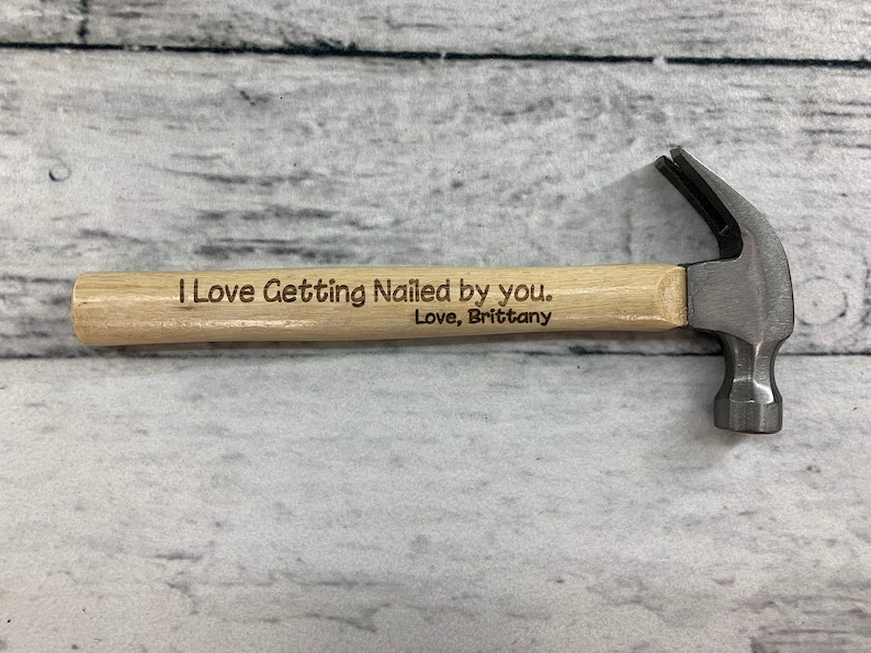 May include: A small wooden handled hammer with a metal head. The handle is engraved with the text "I Love Getting Nailed by you. Love, Brittany."