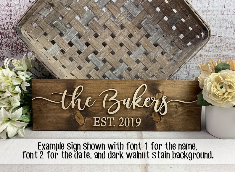 May include: A wooden sign with the text "the Bakers EST. 2019" in a cursive font. The sign is stained a dark walnut color.