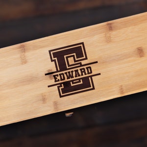 May include: A personalized bamboo cutting board with the letter "E" and the name "EDWARD" engraved in a varsity-style font.