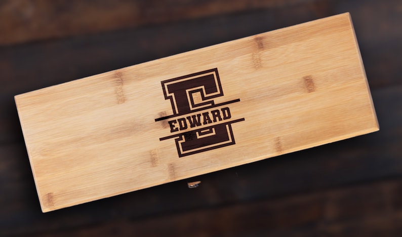 May include: A personalized bamboo cutting board with the letter "E" and the name "EDWARD" engraved in a varsity-style font.