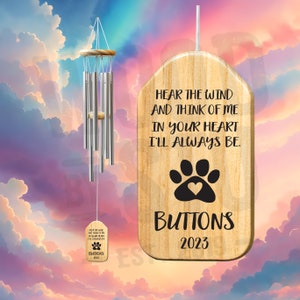 May include: A wooden wind chime with a paw print and the text "Hear the wind and think of me in your heart I'll always be. Buttons 2023"
