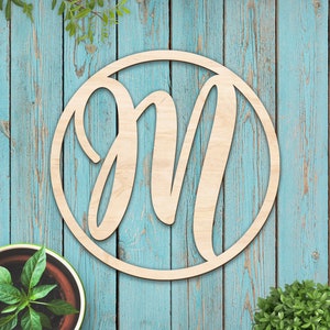 May include: A wooden circle with a cursive letter "M" cut out. The circle is light brown and the background is a light blue wood grain.