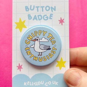 May include: A circular light blue button badge featuring a cartoon seagull and the text "CHIPPY TEA ENTHUSIAST" in yellow. The badge is attached to a white rectangular backing card with a grid pattern, yellow and pink stars, and the text "KELLYLOU.CO.UK".