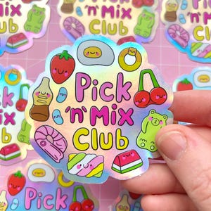 May include: A holographic sticker with a pink, yellow and blue colour scheme. The sticker features a variety of cartoon candy and food items, including a gummy bear, a cherry, a watermelon slice and a donut. The text "Pick 'n Mix Club" is written in pink and yellow letters.