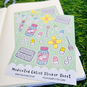 May include: A sticker sheet with a green background featuring various cute pill and medical-themed illustrations. The sheet includes happy pills, bandages, spoons, and pill bottles. The text "Medicated Cuties Sticker Sheet" is printed at the bottom of the sheet.