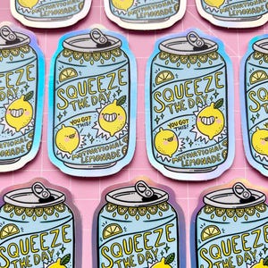 May include: A set of nine holographic stickers featuring a blue can with a yellow lemon and the text "Squeeze the Day! You Got This! Motivational Lemonade".