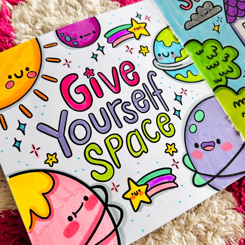 May include: A colourful illustration with the text "Give Yourself Space" surrounded by planets, stars, and rainbows. The planets have cute faces and are drawn in a cartoon style.