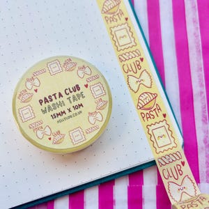 Könnte beinhalten: Eine Rolle gelbes Washi-Tape mit einem sich wiederholenden Muster aus Pastaförmchen und den Worten "PASTA CLUB". Ein Streifen des gleichen Tapes ist abgerollt und zeigt das Design. Das Tape ist 15 mm x 10 m groß.