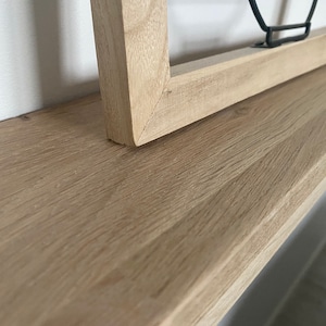 May include: A close-up of a light wood shelf with a natural wood grain. The shelf is made of solid wood and has a smooth, polished finish.