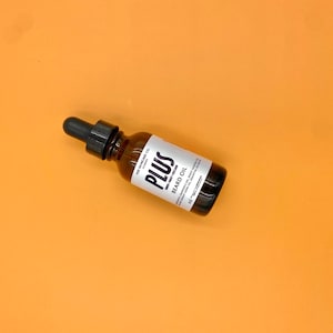 May include: A brown glass bottle with a dropper top, labeled "PLUS Beard Oil" with the text "YEE SKINCARE CO. PRESENT" on the bottle.