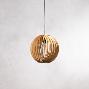 May include: A wooden pendant light with a round, slatted shade. The light is hanging from a black cord.