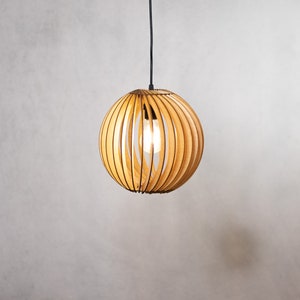 May include: A wooden pendant light with a round, slatted shade. The light is turned on and illuminates the room.