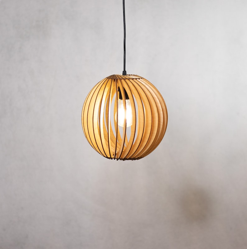 May include: A wooden pendant light with a round, slatted shade. The light is turned on and illuminates the room.