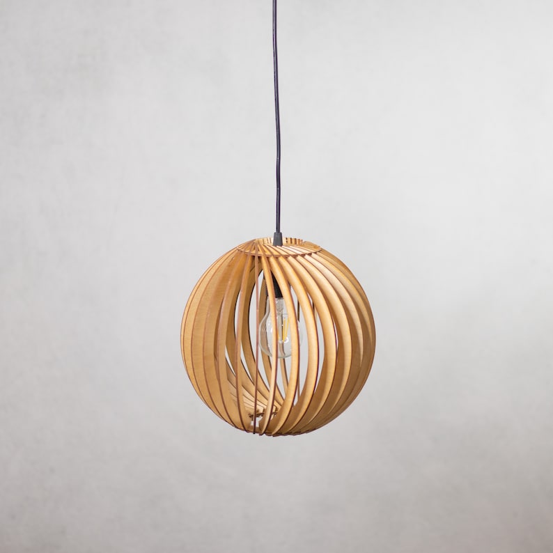 May include: A wooden pendant light with a round, slatted shade. The shade is made of light brown wood and has a black cord.