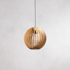 May include: A wooden pendant light with a round, slatted shade. The light is hanging from a black cord.