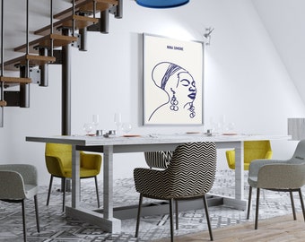Op de afbeelding: Een eetkamer met een rechthoekige tafel en zes stoelen. Een ingelijste print van Nina Simone in blauwe inkt hangt aan de muur. De stoelen zijn grijs, geel en met patronen. Een houten trap is zichtbaar.