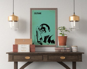 Op de afbeelding: Een ingelijste poster met een turquoise achtergrond en een zwart silhouet van een persoon die saxofoon speelt. De poster heeft het woord "COLTRANE" in zwart bovenaan gedrukt.