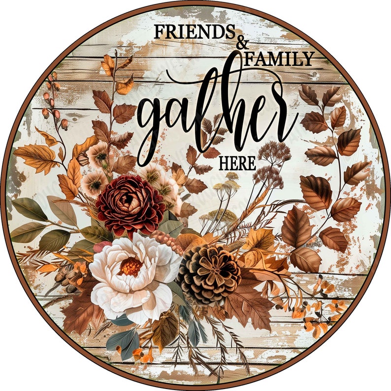 May include: A round wooden sign with a distressed white wood grain background. The text reads FRIENDS & FAMILY gather HERE in black script and serif fonts. An arrangement of brown autumn leaves, a dark red flower, a white flower, and a pinecone.