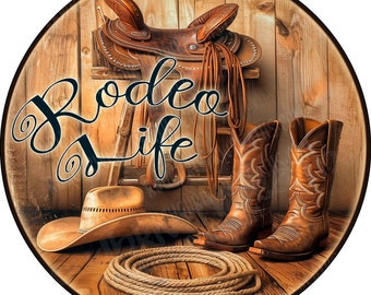 May include: A circular sign featuring a brown leather saddle on a wooden stand, a pair of brown leather cowboy boots, a tan cowboy hat, and a coiled rope. The text "Rodeo life" is written in a black cursive script across the center of the image.