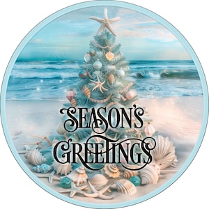 May include: A circular sign featuring a light blue Christmas tree decorated with seashells and starfish on a sandy beach by the ocean. The text "SEASON'S GREETINGS" is printed in black, stylized lettering across the center of the image.